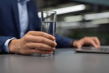 Bilgisayar üzerinde çalışırken su içen tanınmayan yönetici