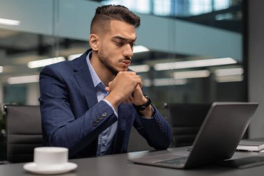 Düşünceli Orta Doğulu işadamı defter ekranına bakıyor