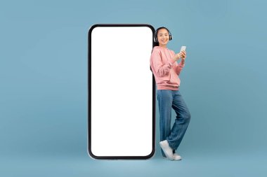 Kulaklık ve akıllı telefonlu neşeli Asyalı kadın.