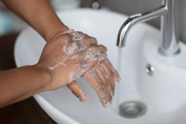Concetto di lavaggio a mano. Giovane uomo indiano lavarsi le mani con sapone antibatterico sotto l'acqua di rubinetto caduta in lavabo — Foto Stock