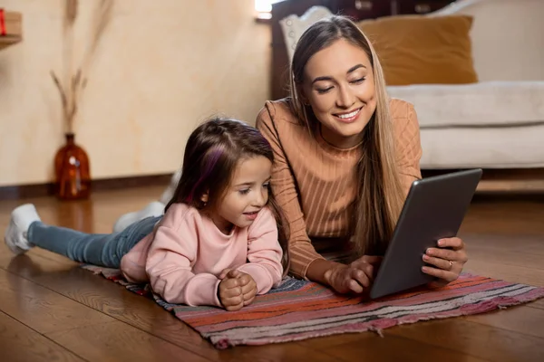 Lachende vrouw en meisje met behulp van tablet thuis — Stockfoto