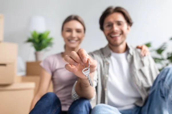 Froh glücklich jung europäisch ehemann in brille und ehefrau zeigt schlüssel aus neue eigene wohnung im zimmer interieur — Stockfoto