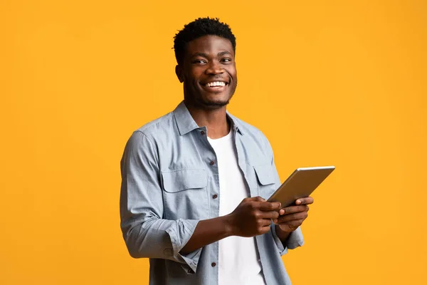 Emocjonalny Afroamerykanin trzymający cyfrową tabletkę i uśmiechający się — Zdjęcie stockowe