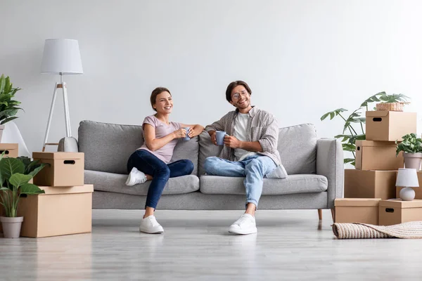 Sorrindo sonhando europeu millennial família relaxante no sofá na sala de estar interior com caixas de papelão — Fotografia de Stock