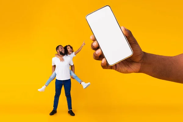 흑인 아버지와 딸 이 흉내를 내기 위해 빈 스마트폰 화면을 보여 주고 있다 — 스톡 사진