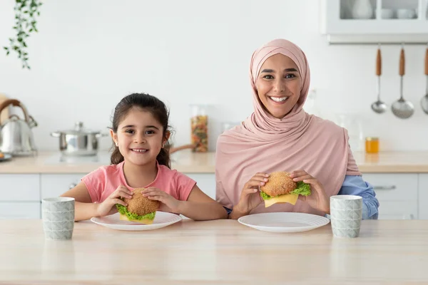 Aile Beslenmesi. İslami Kadın ve küçük kızı mutfakta sandviç yiyorlar. — Stok fotoğraf