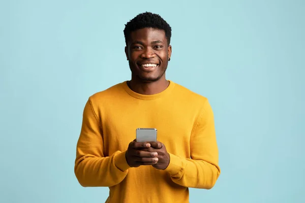 Gelukkig afrikaanse amerikaan guy holding mobiele telefoon en glimlachen — Stockfoto