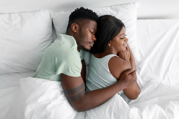 Sakin, neşeli, bin yıllık Afro-Amerikan kocası karısına sarılıyor ve uyuyor, dinleniyor, rahatlıyor. — Stok fotoğraf