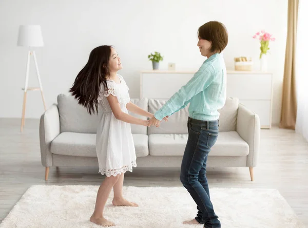 Feliz niña asiática y su abuela tomados de la mano y bailando en casa —  Fotos de Stock