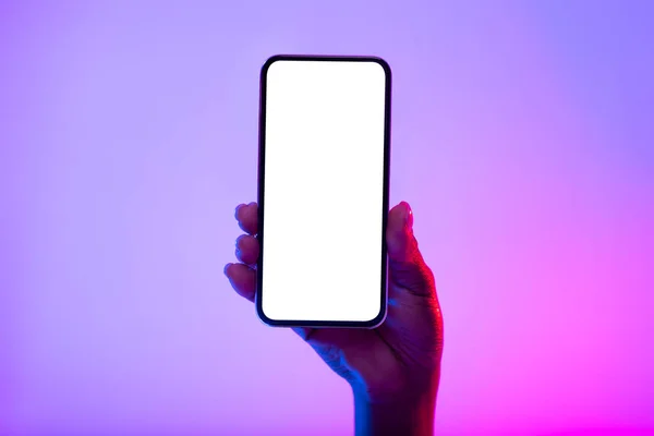 Cropped view of African American female showing cellphone with empty white screen in neon light, mockup — Stock Photo, Image