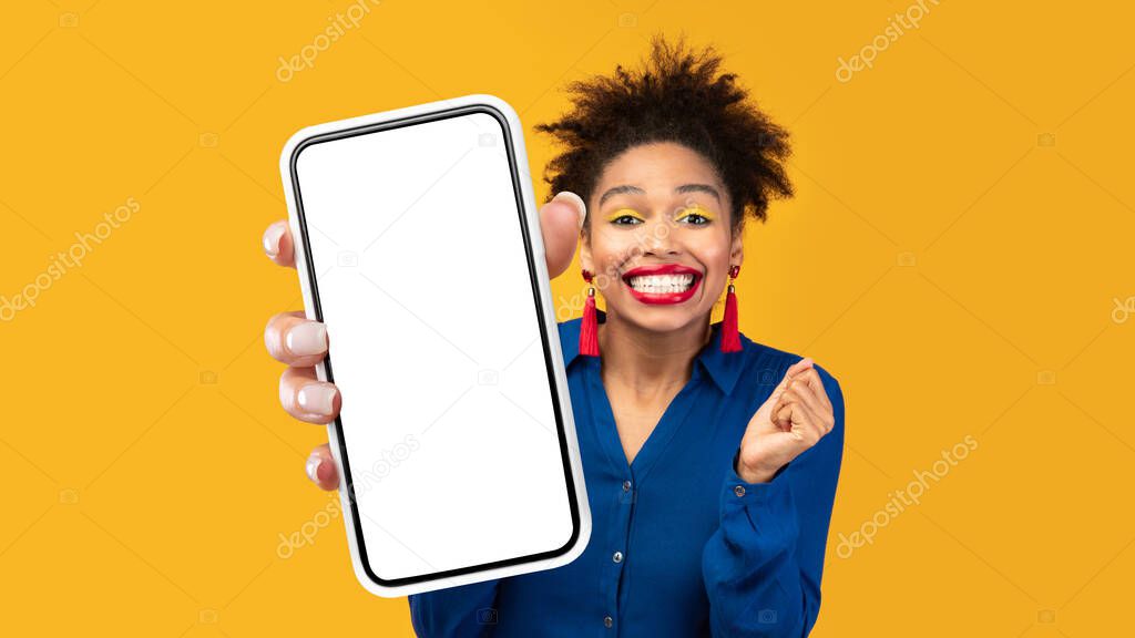 Joyful Black Lady Showing Big Smartphone Empty Screen, Yellow Background