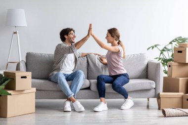 Tatmin olmuş Avrupalı genç karı koca oturma odasındaki koltukta kutular içinde beşlik çakıyor.