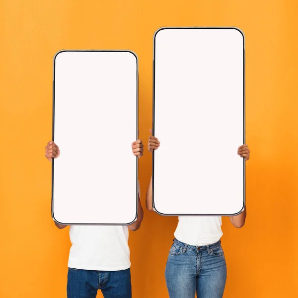 Casal jovem mostrando telas de smartphones vazias em branco para mockup — Fotografia de Stock