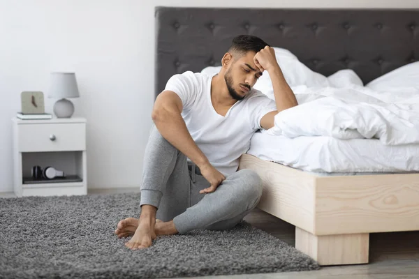 Conceito de Doença Mental. Deprimido jovem árabe cara sentado no chão perto da cama — Fotografia de Stock