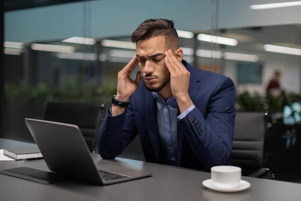 Уставший араб-предприниматель, страдающий головной болью, офисный интерьер — стоковое фото