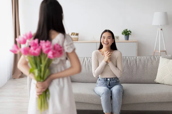 Liten asiatisk flicka som håller bukett med blommor bakom ryggen, vilket gör semester överraskning för mor, firar kvinnodagen — Stockfoto