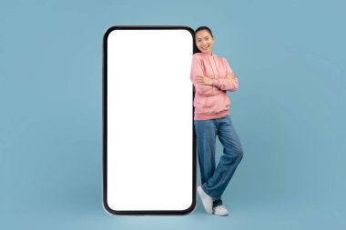 Büyük cep telefonuyla poz veren Koreli kadının tam ekran görüntüsü.