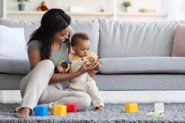 Bebeklerle Faaliyet. Siyah anne, evde bebekle oyuncak oynuyor.