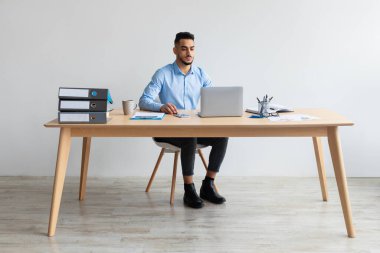 Arap adam ofiste dizüstü bilgisayar kullanıyor.