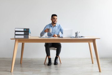 Arap adam ofiste dizüstü bilgisayar kullanıyor.