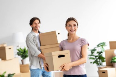 Gülümseyen, bin yıllık beyaz aile eşyaları toplayan, iç odada karton kutular taşıyan, taşınmaktan zevk alan