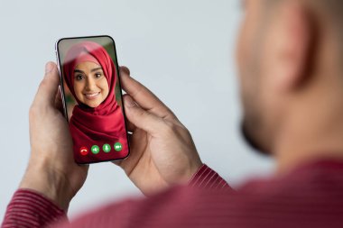 Tanımlanamayan bir Arap, karısıyla çevrimiçi sohbet etmek için akıllı telefon kullanıyor. Video çağrısı, kolaj aracılığıyla uzaktan konuşuyor.