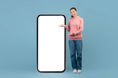 Pozitif Çinli kadın boş ekranla akıllı telefonu işaret ediyor.