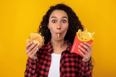 Lezzetli patates kızartması ve hamburger yiyen heyecanlı bayan.