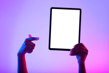 Tanımlanamayan siyah kadın boş tableti işaret ediyor, yeni uygulama öneriyor, neon ışıklı reklam sitesi, model