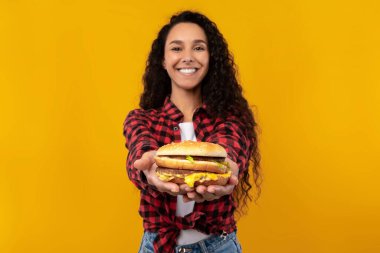 Stüdyoda hamburger tutan ve veren mutlu genç bayan.