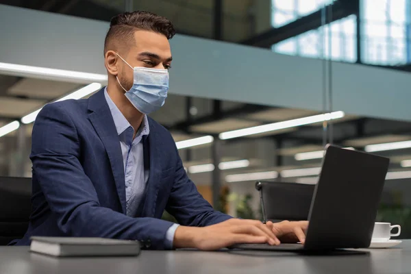 Empresário em máscara facial digitando no teclado do laptop — Fotografia de Stock