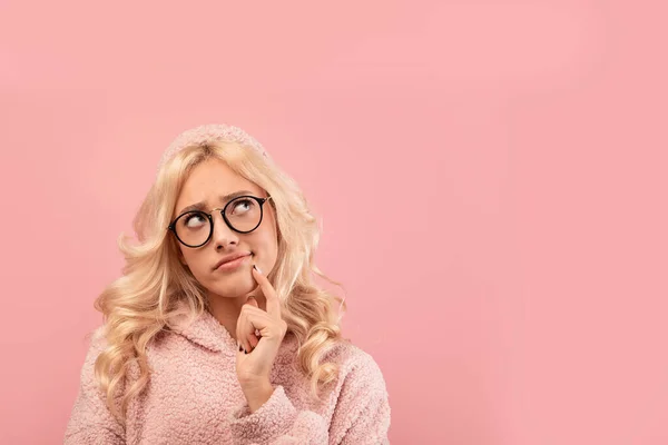 Mulher loira pensativa em óculos olhando para o espaço de cópia, de pé sobre fundo de estúdio rosa, design de banner — Fotografia de Stock