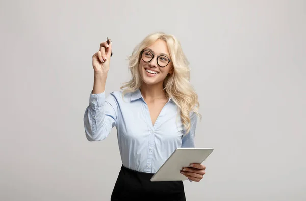 Kluge junge Geschäftsfrau mit Markierungsschrift oder Zeichnung auf virtuellem Bildschirm vor hellgrauem Hintergrund — Stockfoto