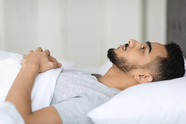 Álmatlanság koncepció. Fiatal közel-keleti férfi fekszik az ágyban nyitott szemmel — Stock Fotó