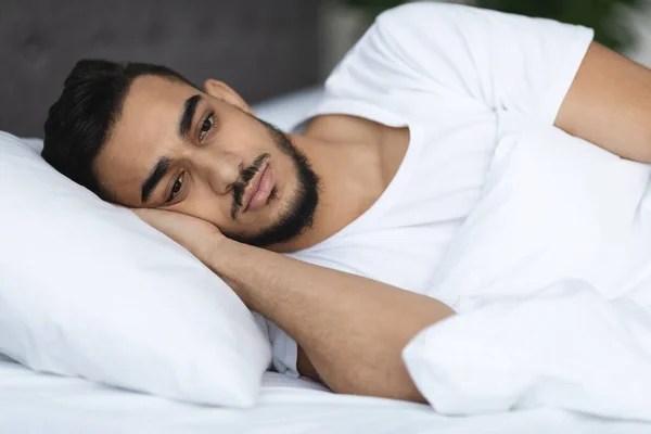 Alvászavarok. Feldúlt arab férfi fekszik az ágyban nyitott szemmel. Közelkép — Stock Fotó