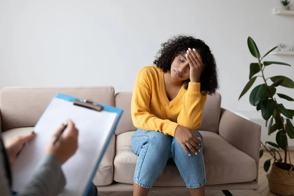 Mujer negra deprimida que consulta con psicólogo, que sufre de trastorno de estrés postraumático en la clínica mental —  Fotos de Stock