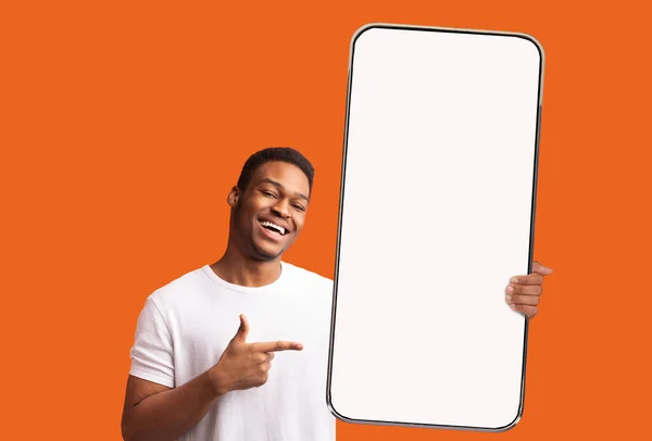 Черный парень указывает на белый пустой экран смартфона — стоковое фото