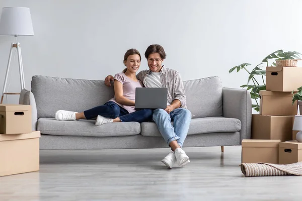 Upptagen glad europeisk ung man visa dator till kvinna på soffan i vardagsrummet interiör — Stockfoto