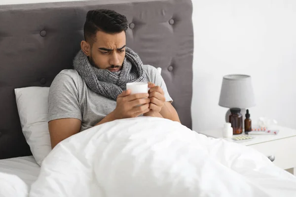 Κρύο και γρίπη. Πορτρέτο του άρρωστου Άραβα άνδρα πίνοντας τσάι στο κρεβάτι — Φωτογραφία Αρχείου