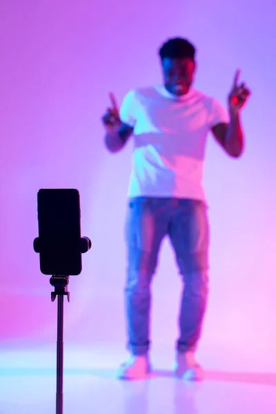 Fekete férfi befolyásoló forgatás videó a közösségi média mobiltelefon, szórakozás neon fény, mockup — Stock Fotó