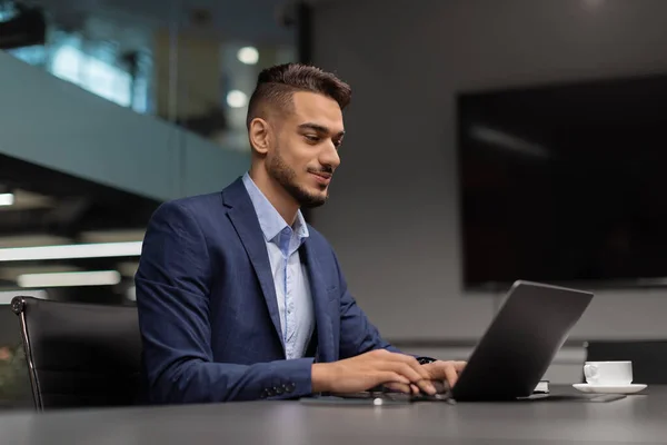 Side view of middle eastern businessman typing on notebook — Stock Photo, Image