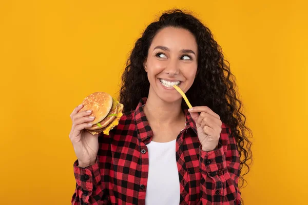 Emocionado Lady comiendo deliciosas papas fritas y hamburguesas — Foto de Stock