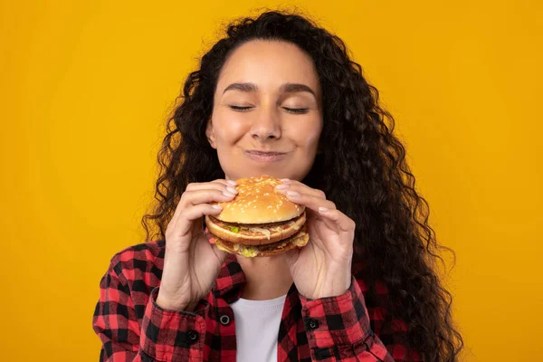 Closeup van opgewonden dame eten smakelijke hamburger in Studio — Stockfoto