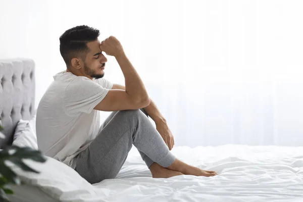 Portrét depresivní mladý muž ze Středního východu sedí na posteli v ložnici — Stock fotografie