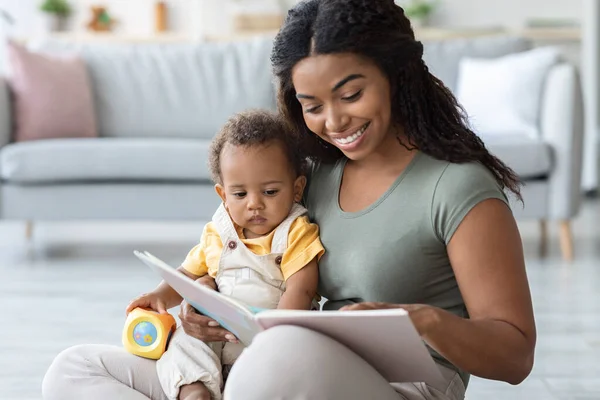 Gelukkig zwart familie moeder met schattige zuigeling zoon lezen boek thuis — Stockfoto