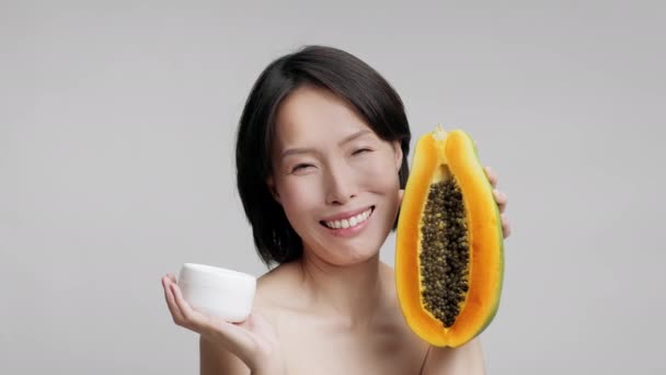 Зріла японська жінка holding papaya і mourizer над сірий фон — стокове відео