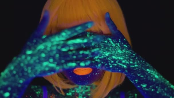 Jonge aziatische vrouw met heldere neon lichaam kunst poseren om camera, gebaren met gloeiende kleurrijke handen in uv licht — Stockvideo