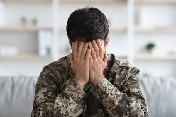 Closeup portrait of military man covering his face with palms