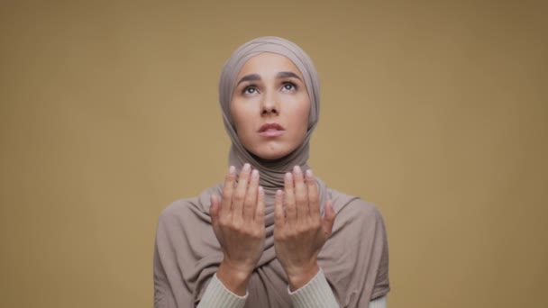 Religion and faith. Portrait of young peaceful muslim lady praying to god, doing islamic hands gesture and talking — Stock Video