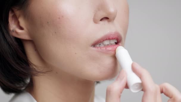 Irreconocible maduro asiático mujer aplicando bálsamo labial sobre gris fondo — Vídeos de Stock